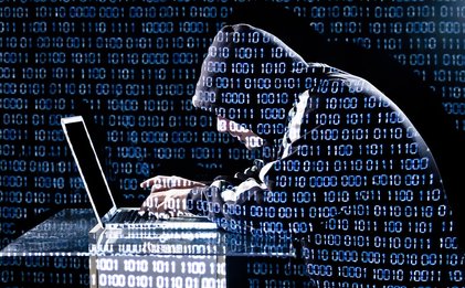 Man in Hood working on Laptop with binary code overlaid onto the entire picture