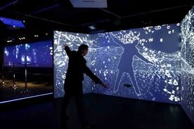 Man Standing at a simulator which allows him to interact with the picture being displayed