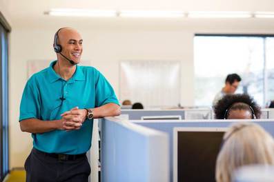 Man standing in front of people sitting in cubicles